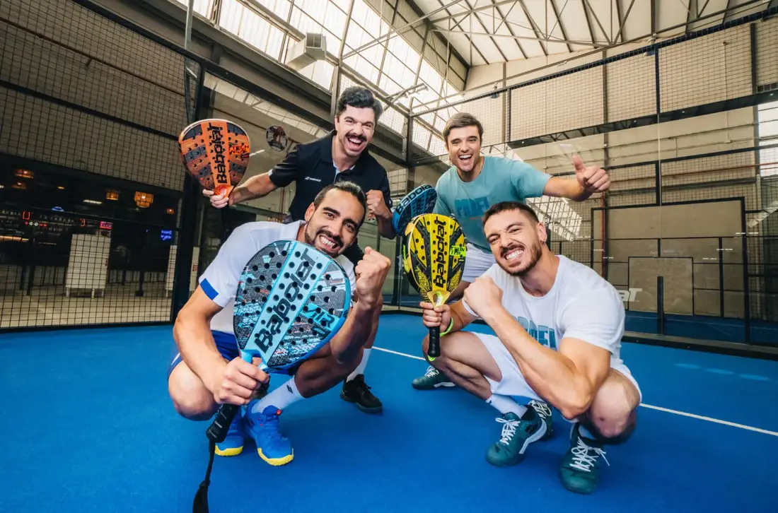Indoor padel court with glass walls at Padel Den Orem showing four players with rackets