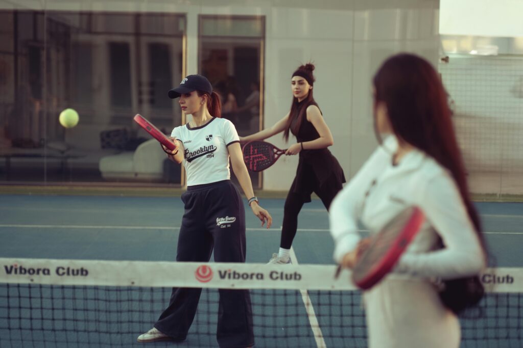 Women playing a social game of padel tennis doubles on an outdoor court.