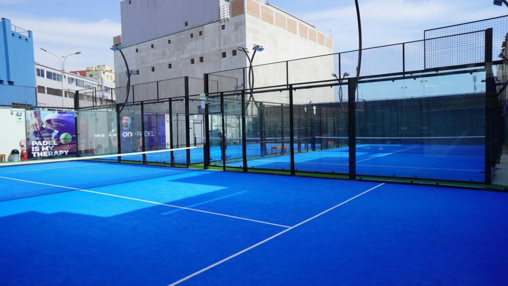 Bright blue padel court showing the glass walls used for strategic play in adult sports leagues in Utah.