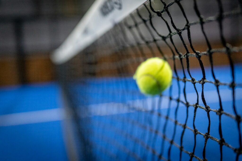 A close-up of a ball hitting the net during a fast-paced match at an indoor padel club in Orem.