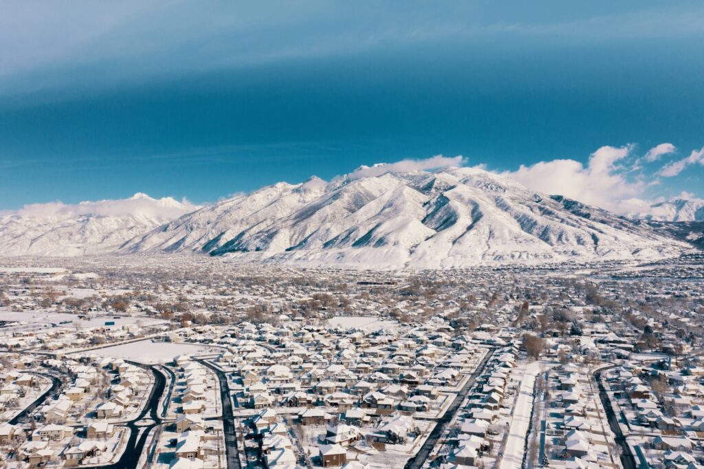 Aerial view of snow-covered homes and mountains in Utah, showing why locals constantly search for weather-proof indoor activities in Utah County.