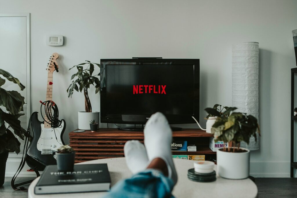A person relaxing on a couch watching Netflix, representing the struggle adults face when looking for new indoor activities in Utah County.