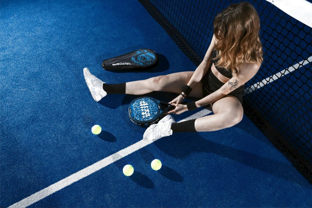 A female player resting comfortably on clean, shock-absorbing artificial turf, proving why padel is the best pickleball alternative in Utah County.