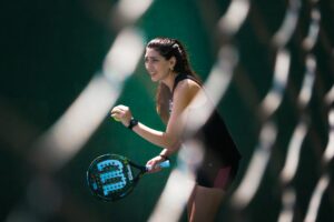 A female athlete holding a solid, stringless racket, highlighting the key differences between standard hardcourts and padel tennis.