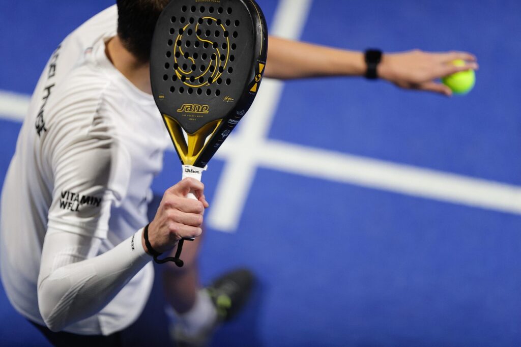 A padel player holding his racket and preparing to serve, demonstrating how to dictate offensive play in a match.