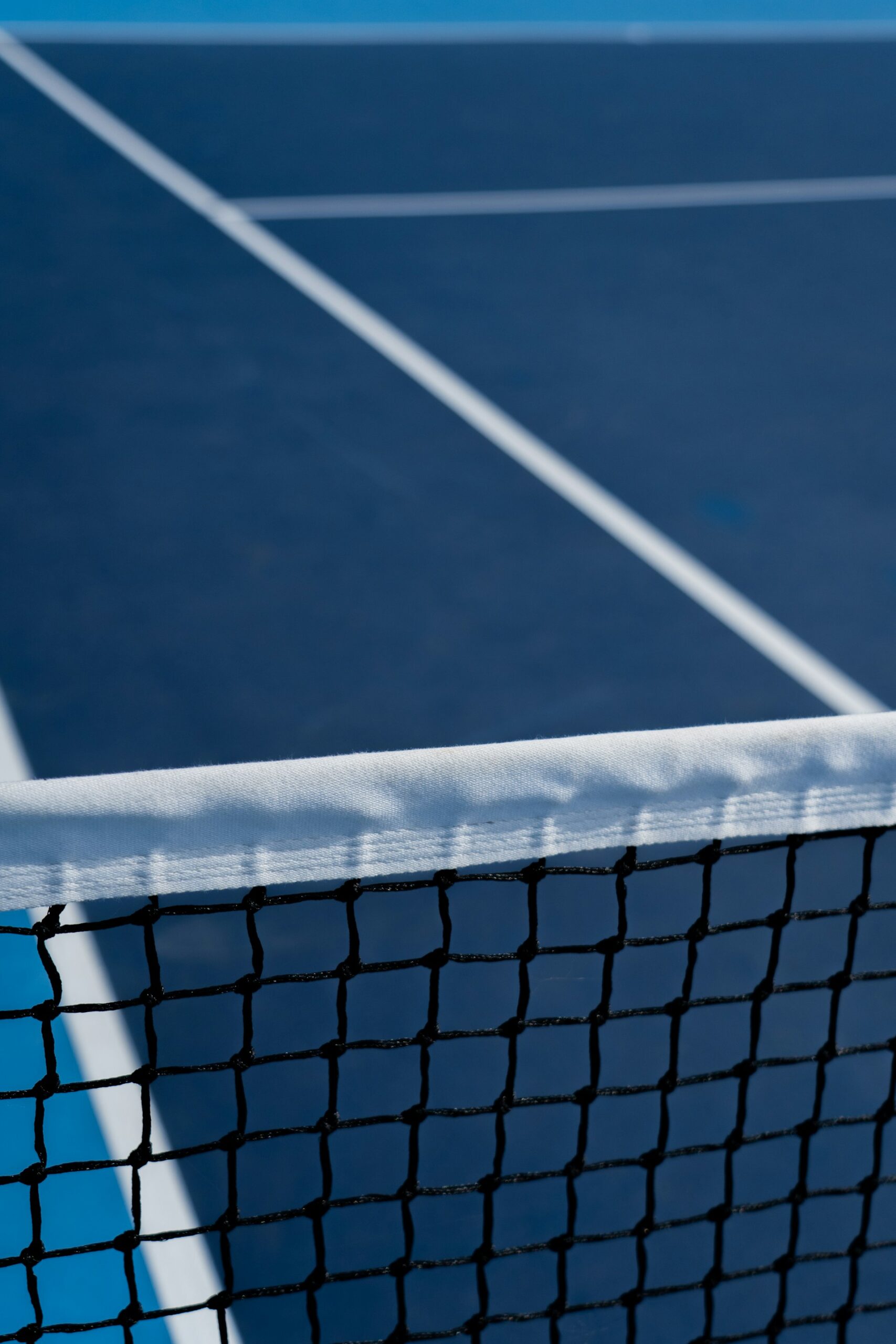 A close-up view of a pristine white net and blue artificial turf on an indoor court, built for the best padel in Utah County.