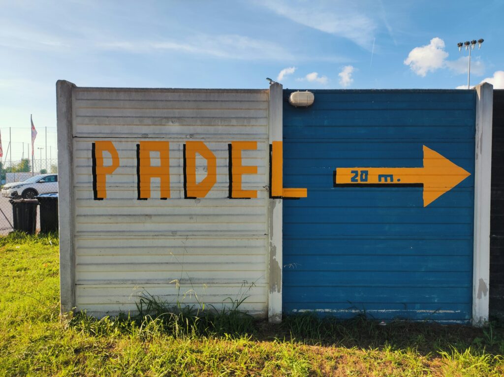A trendy painted sign with a yellow arrow pointing toward a court, guiding players to the best padel Utah has to offer.
