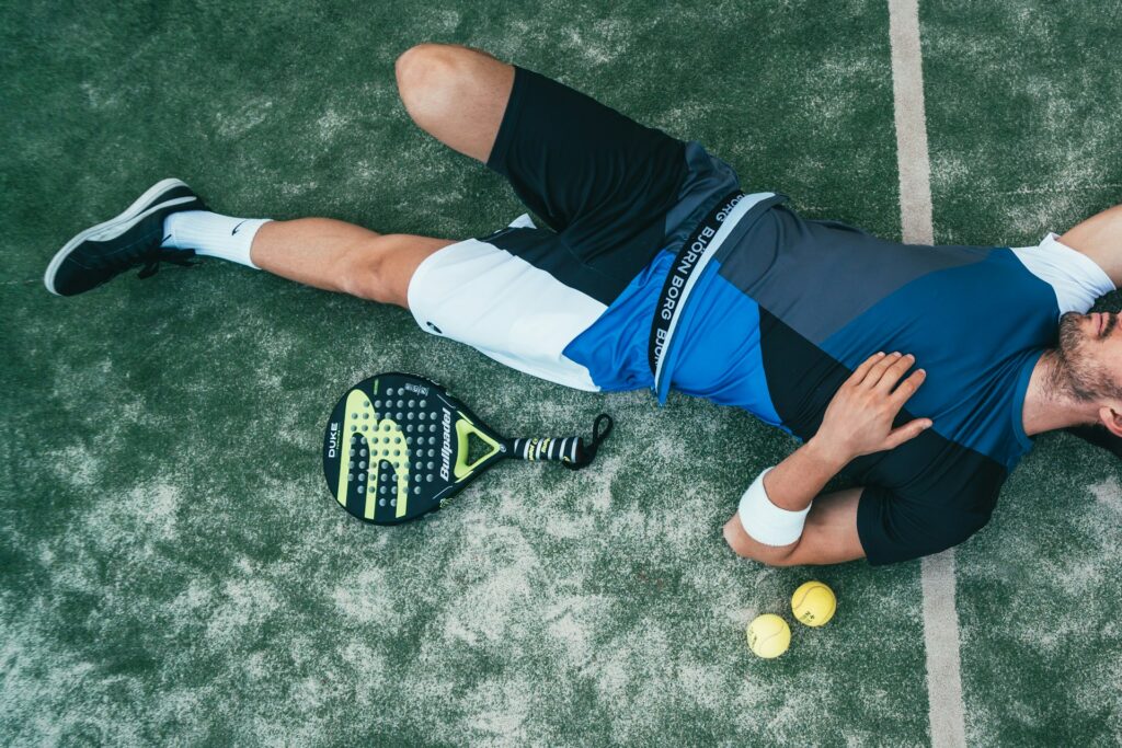 A tired but happy player resting on the court after a massive cardiovascular padel workout.