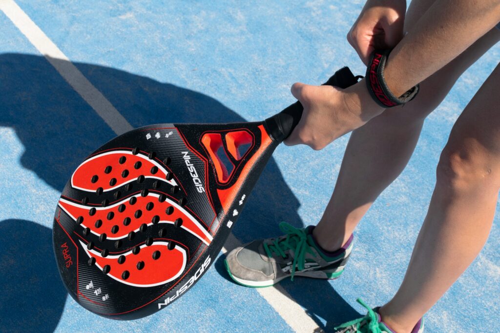 A close-up of a player securing a racket wrist strap, getting ready to experience the active lifestyle of padel Utah.