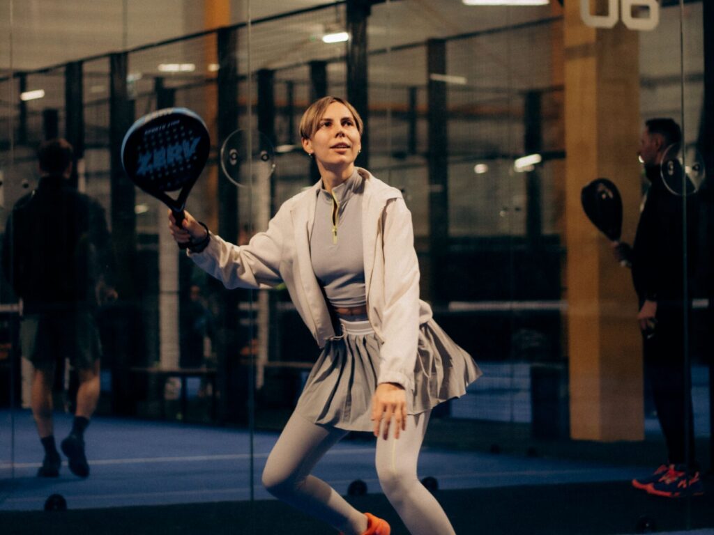A female player moving dynamically on the blue court, demonstrating proper positioning to avoid common beginner mistakes.