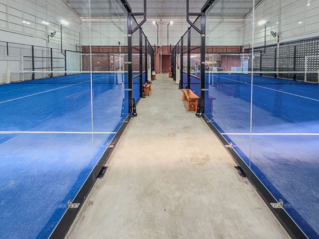 A clean walkway between two indoor padel courts, demonstrating where players should wait and walk safely during court transitions.