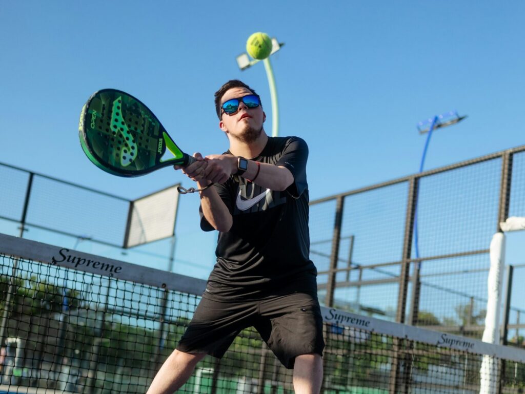 A focused male player executing a controlled two-handed stroke on a blue court.