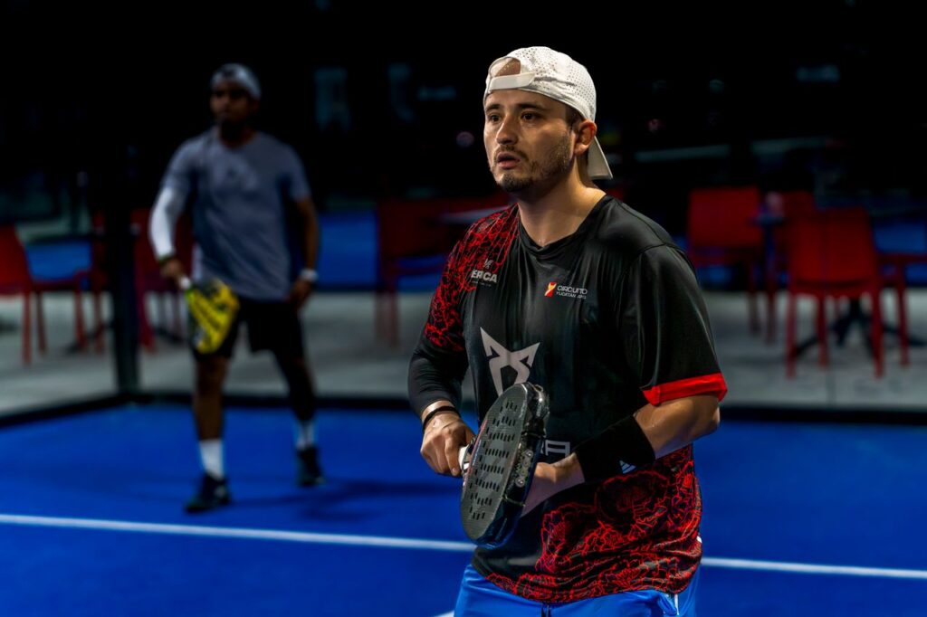 A focused male player in a white backwards cap holding a racket on court, highlighting key strategy tips for transitioning from tennis to padel.