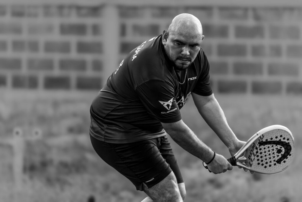 A black and white photo of a player demonstrating a short, compact stroke with a Head padel racket instead of a large tennis backswing.
